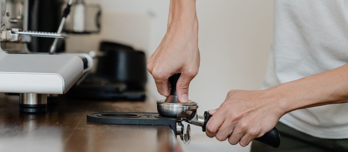 Espresso workflow accessories on a counter — tamper, distributor and tools.