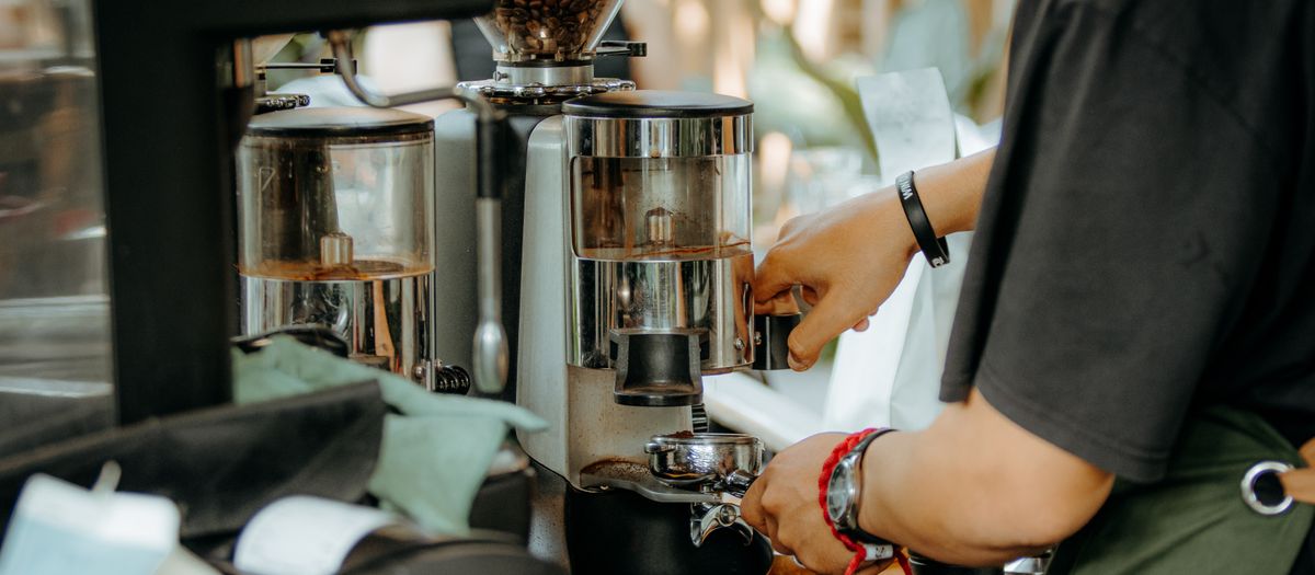 A close-up of an espresso grinder dosing fresh coffee grounds.